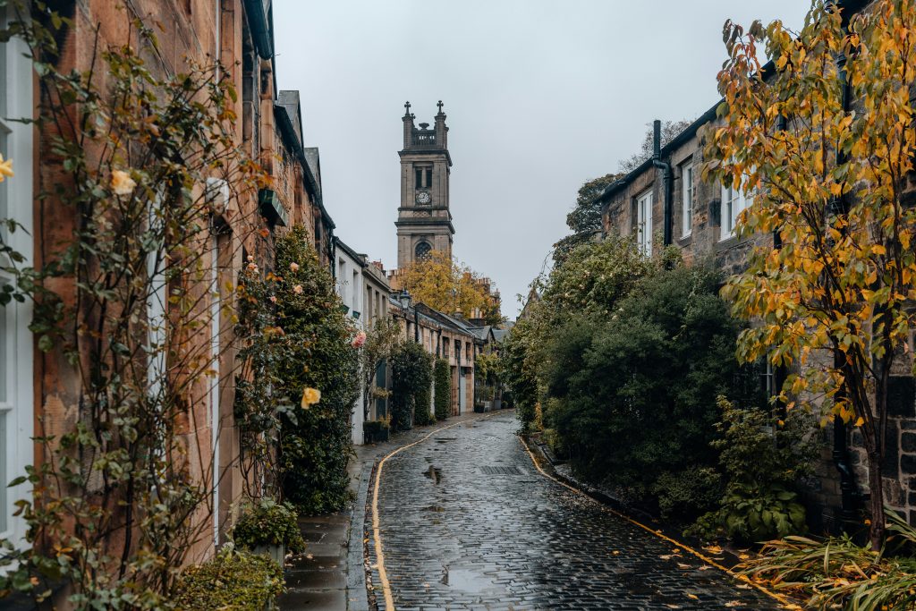 une rue pavée avec une tour de l'horloge en arrière-plan à Edimbourg